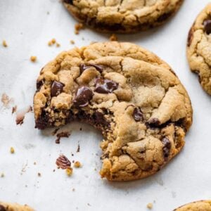 A chocolate chip cookie with a bite taken out of it.