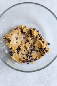 Cookie dough with chocolate chips in a glass bowl.