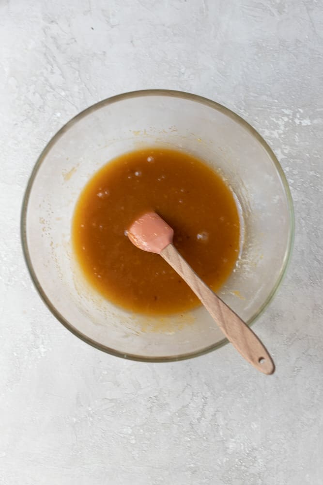 Melted butter and sugar mixed in glass bowl.