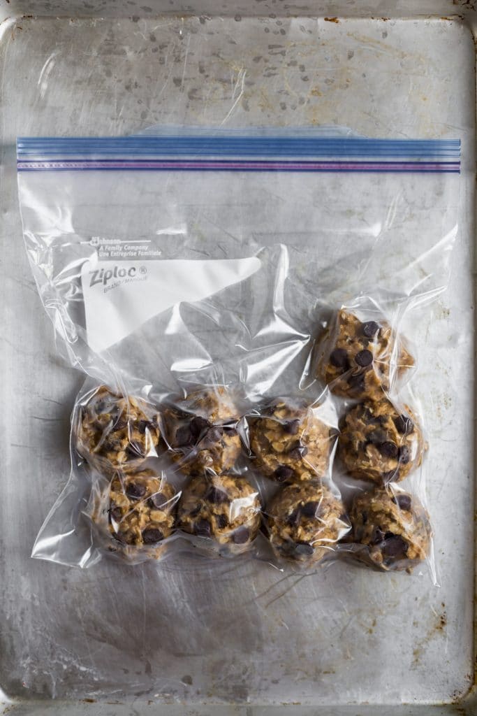 Cookie dough balls lined up in a closed freezer bag on a gray surface.