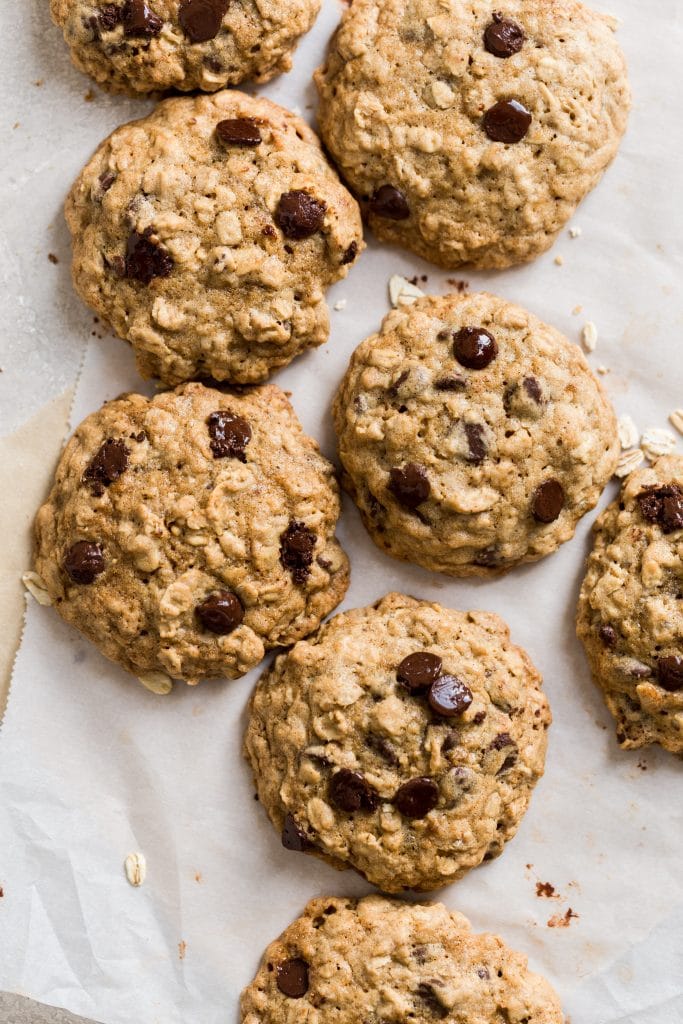 Cookies laying on two sheets on parchment paper on a gray background