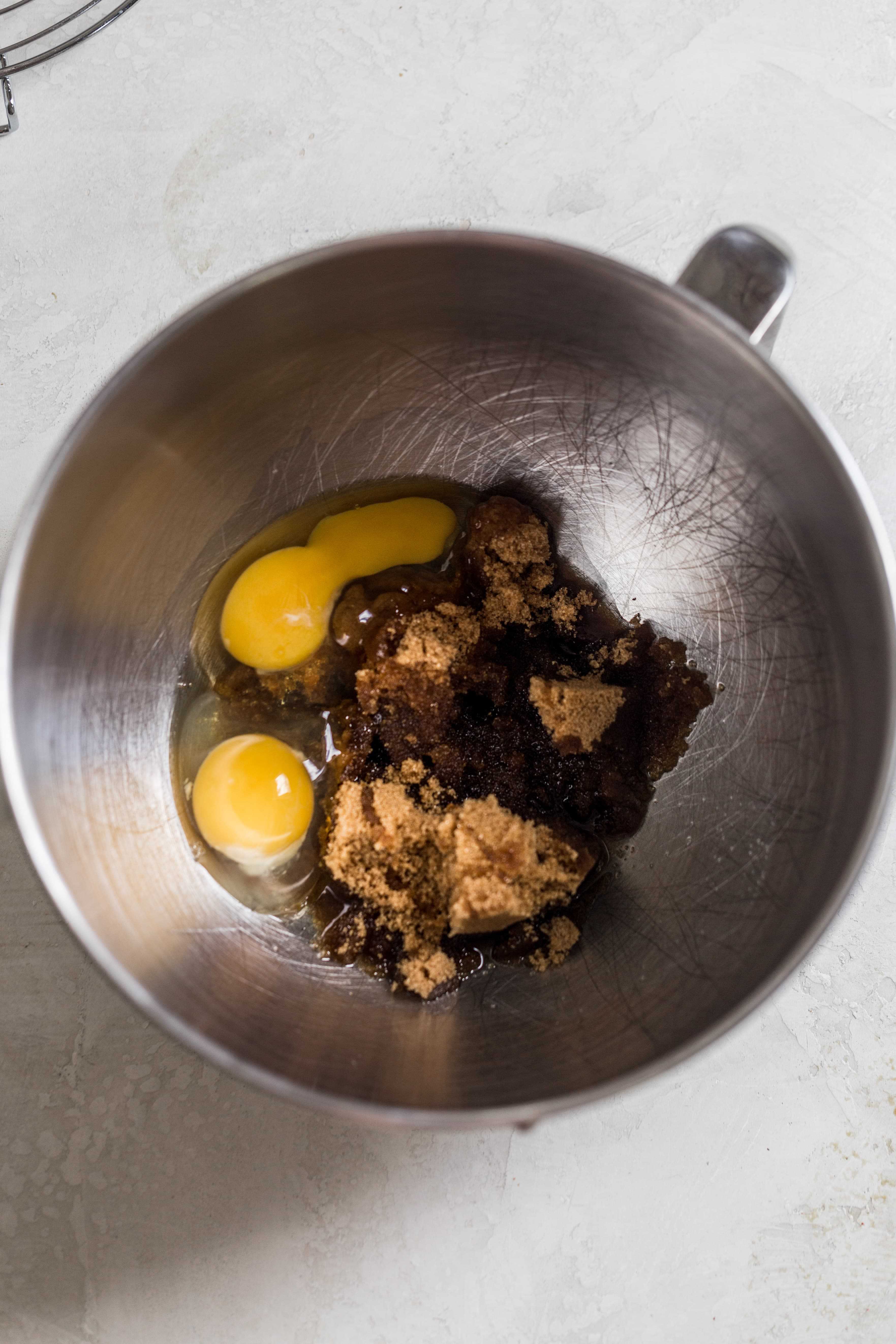 Eggs and sugar in a mixing bowl on a gray surface