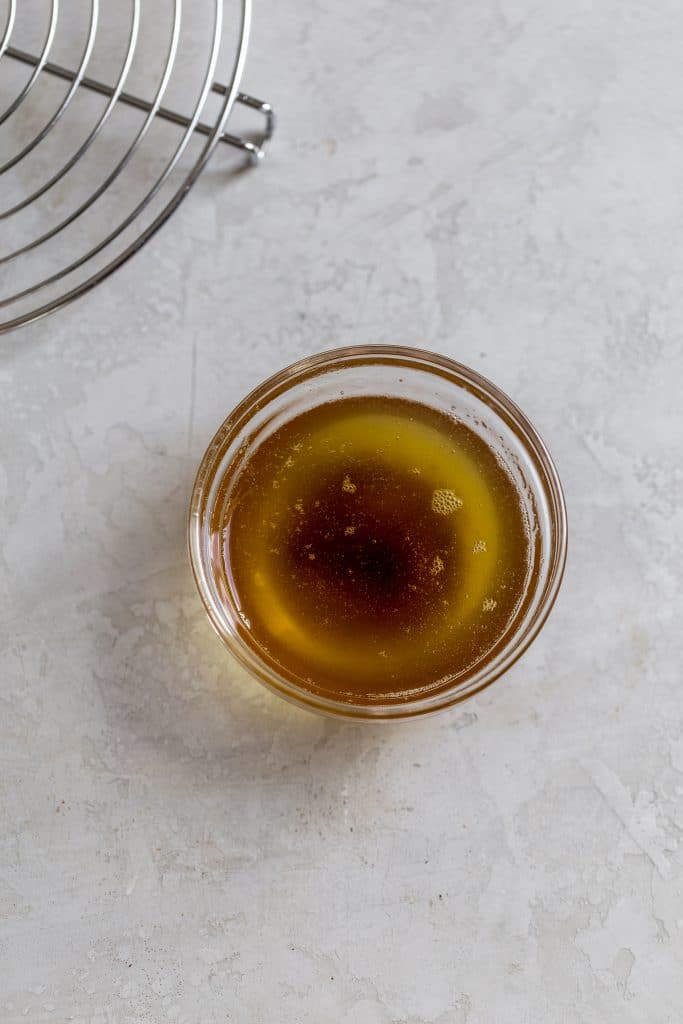 a small glass bowl of brown butter on a gray surface