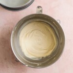 Light yellow cake batter in a mixing bowl on a pink surface