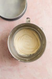 Light yellow cake batter in a mixing bowl on a pink surface