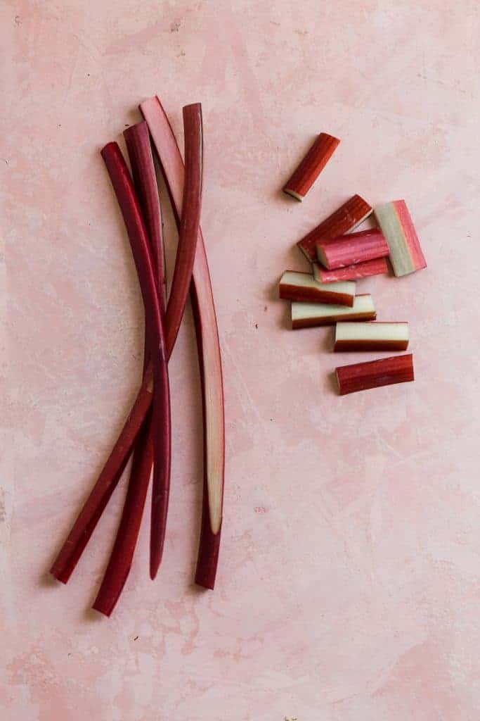 fresh rhubarb in slices and chunks on a pink surface