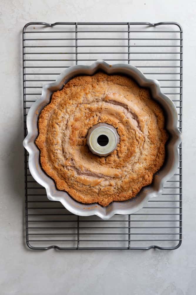 A cake still in the bundt pan on a wire rack