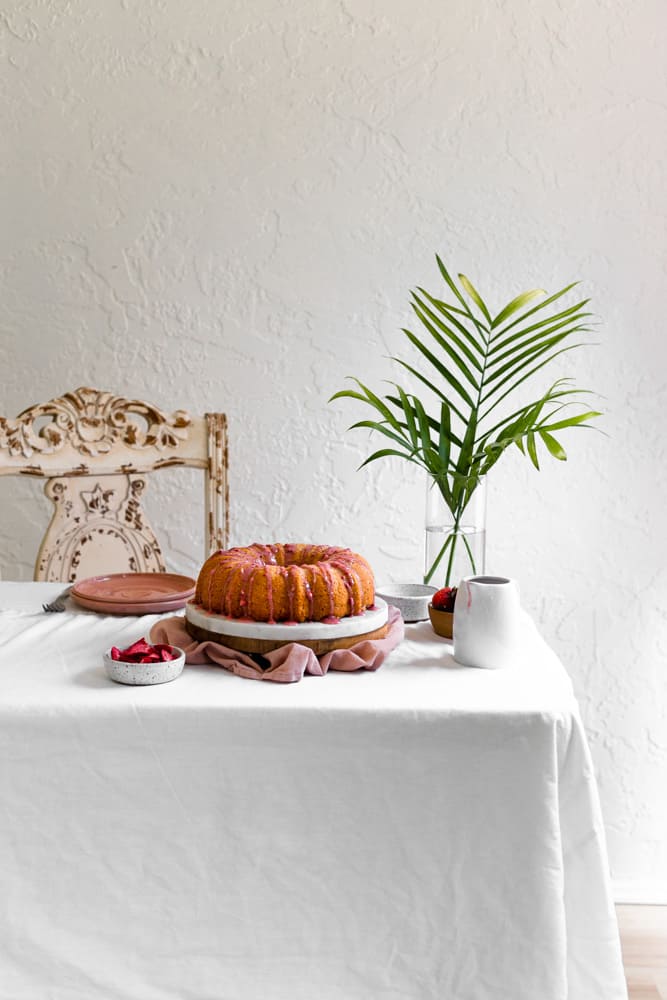 A bundt cake sitting on a white table next to palm fronds