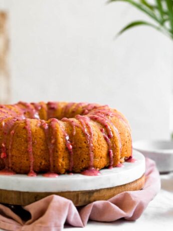 Pink strawberry glaze dripping down a bundt cake next to a white surface