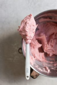 A spatula holding up strawberry pink buttercream