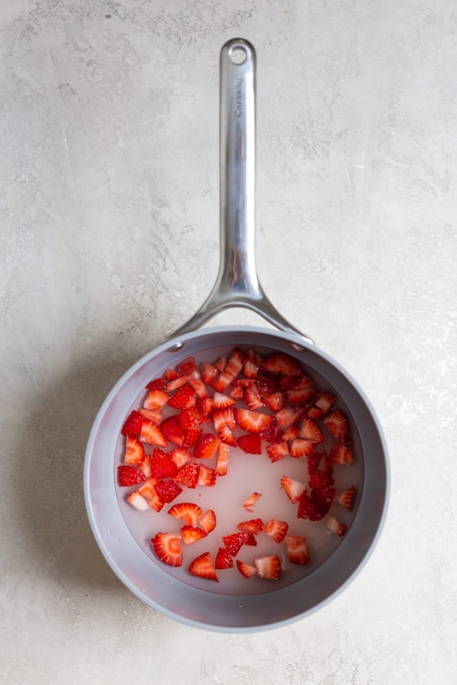 A saucepan filled with strawberries and water