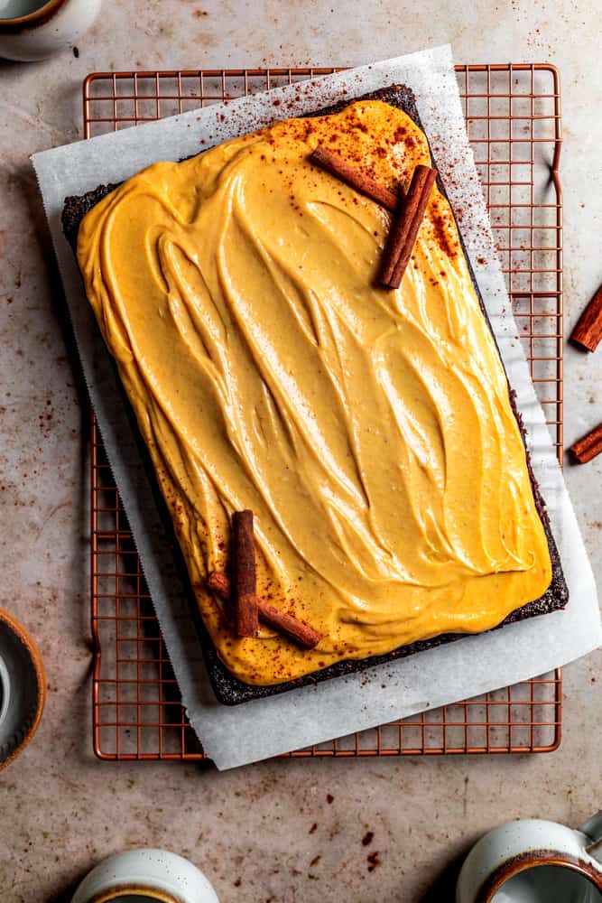 Chocolate pumpkin sheet cake with pumpkin cream cheese frosting decorated with cinnamon sticks.