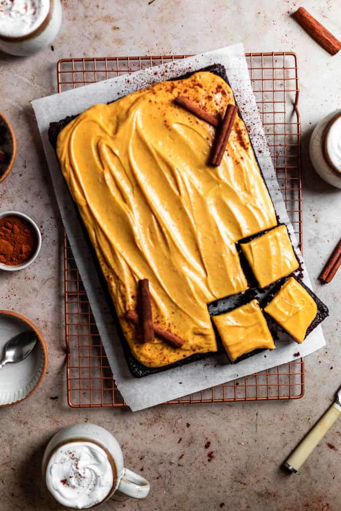 Chocolate pumpkin sheet cake sliced into squares on a piece of parchment paper.