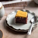 chocolate cake with orange frosting on gray stacked plates on a brown surface