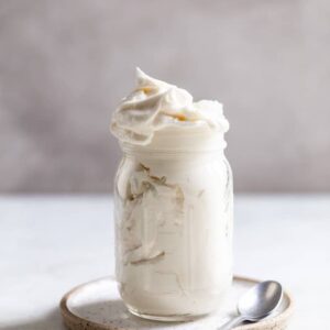 american buttercream frosting in a bell jar on a gray surface