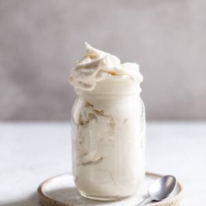 Vanilla frosting in a glass jar on a plate.