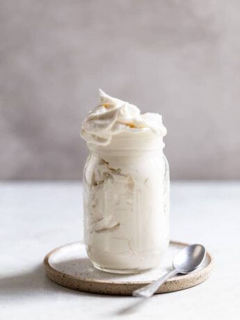 Vanilla frosting in a glass jar on a plate.