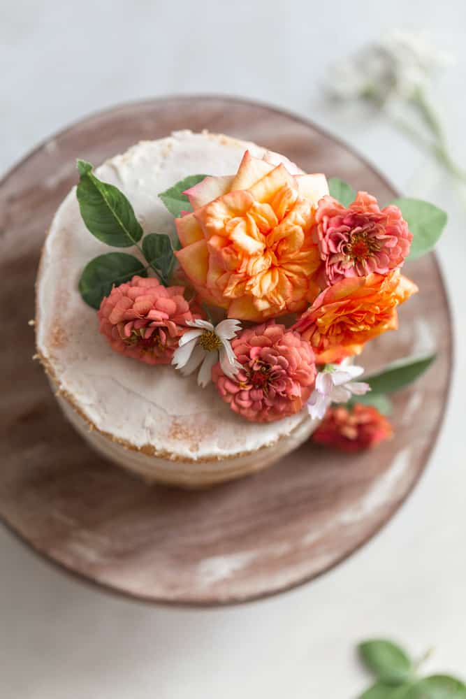 Flowers on a white cake on a wood surface