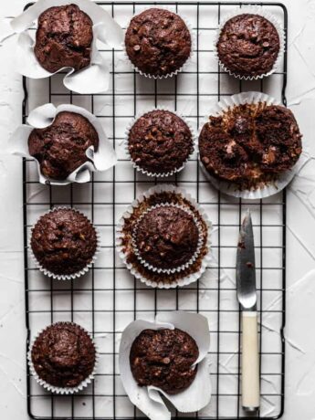 Chocolate banana muffins on a black rack on a gray surface