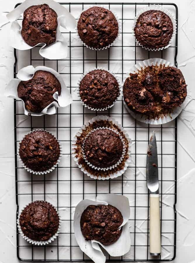 Chocolate banana muffins on a black rack on a gray surface
