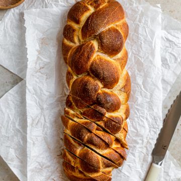 6 strand challah braid sliced on the bottom on a white surface.