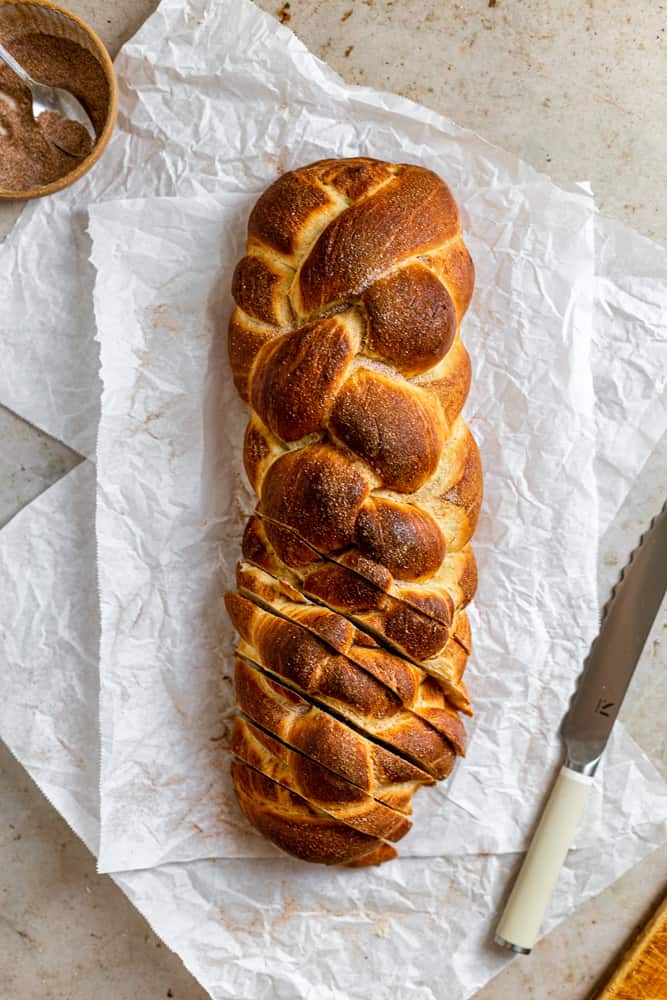 6 strand challah braid sliced on the bottom on a white surface. 
