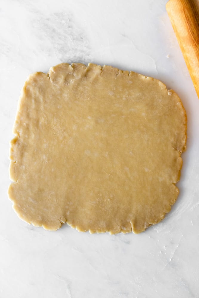pie crust rolled out onto a large circle on a white surface