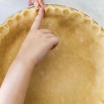 fingers crimping the edges of pie crust