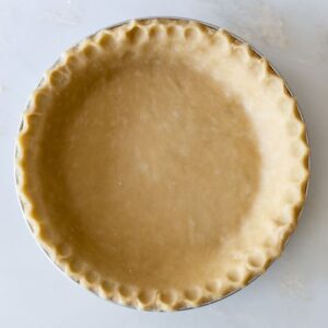 Unbaked pie crust with crimped edges on a white surface