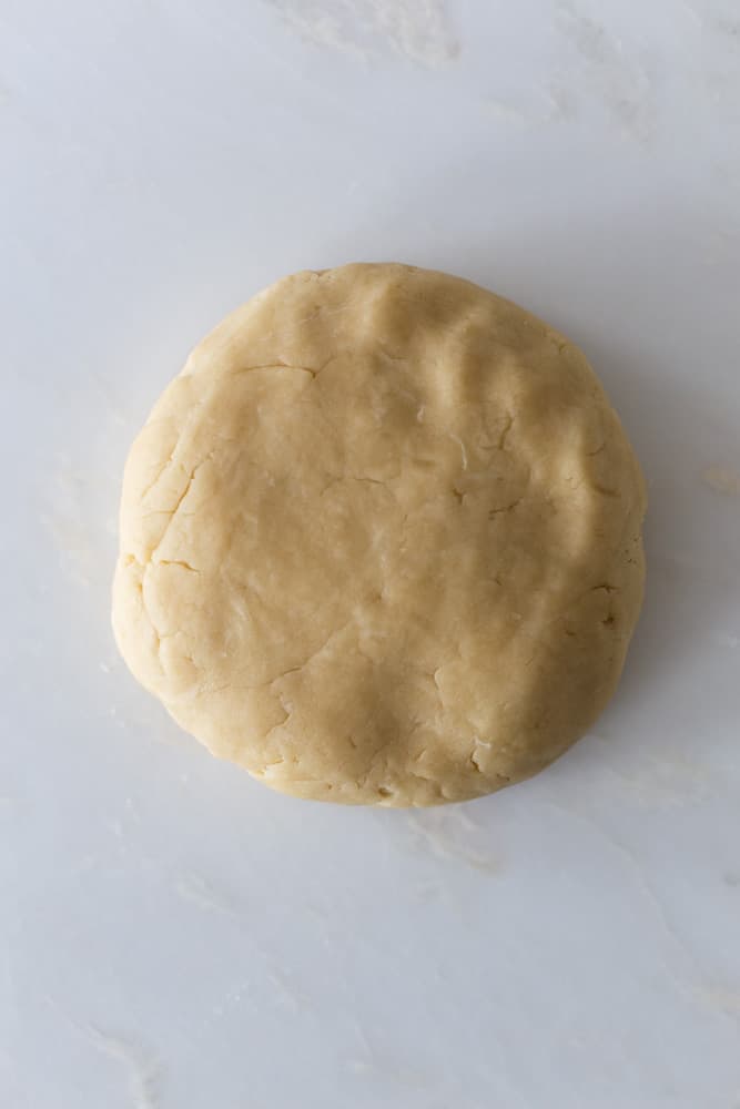 A disc of pie dough on a white surface