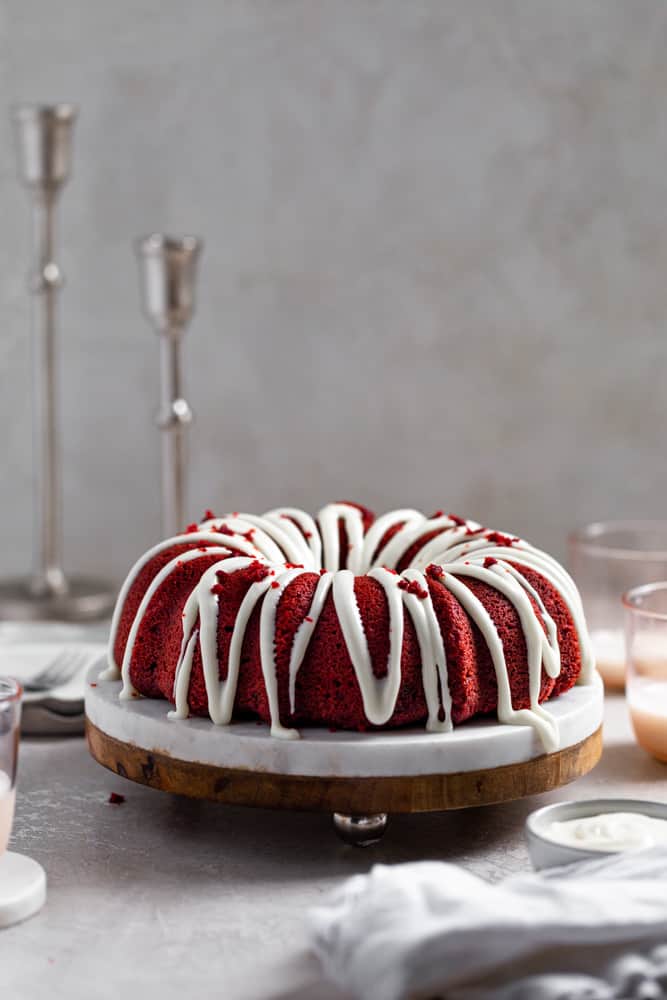 red velvet bundt cake on a marble and wood cake stand on a gray surface