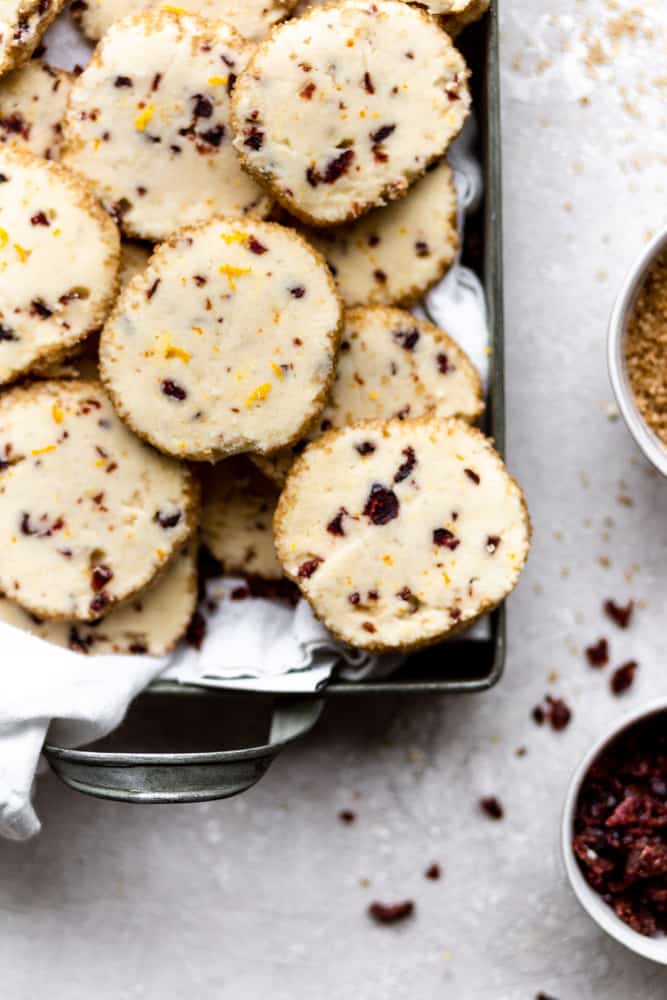 Cranberry orange shortbread cookies in a green tin on a gray background