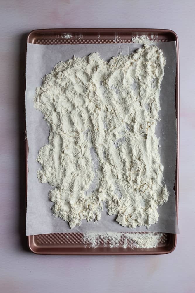 Flour poured onto a baking sheet lined with parchment paper
