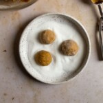 three cookie dough balls rolling in sugar in a bowl