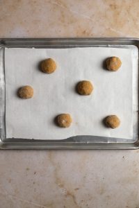 6 cookie dough balls staggerd on a baking tray