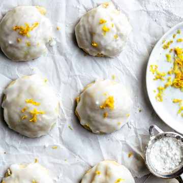 Close up on italian ricotta cookies with lemon zest next to a plate