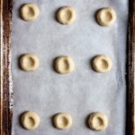 Pressed thumbprint cookie dough on a parchment lined cookie sheet
