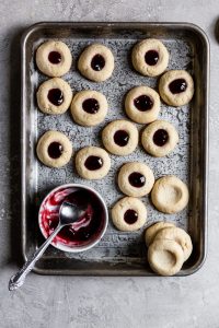Thumbprint cookies filled with jam on a cookie sheet
