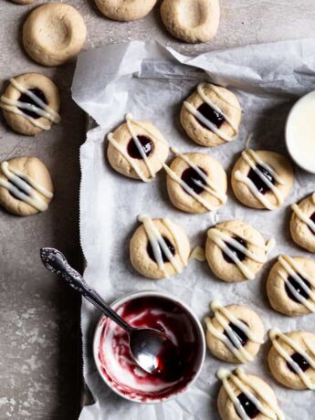 Raspberry thumbprint cookies on a parchment lined cookie sheet