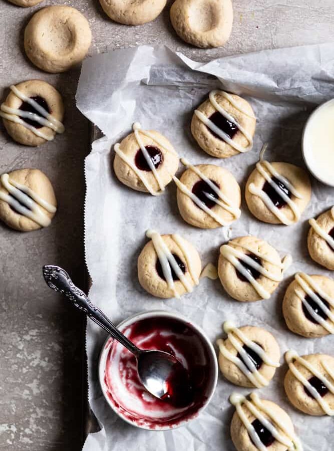 Raspberry thumbprint cookies on a parchment lined cookie sheet