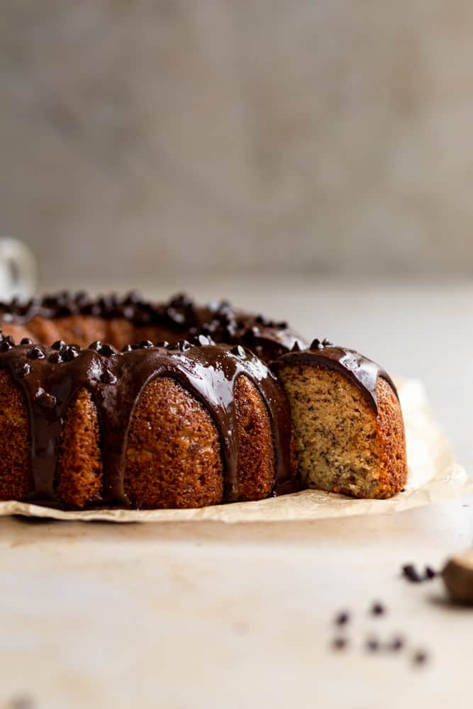 A slice of banana bundt cake pulled out from the rest of the cake on a gray surface