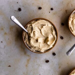 Coffee frosting in a small bowl on a marble backdrop