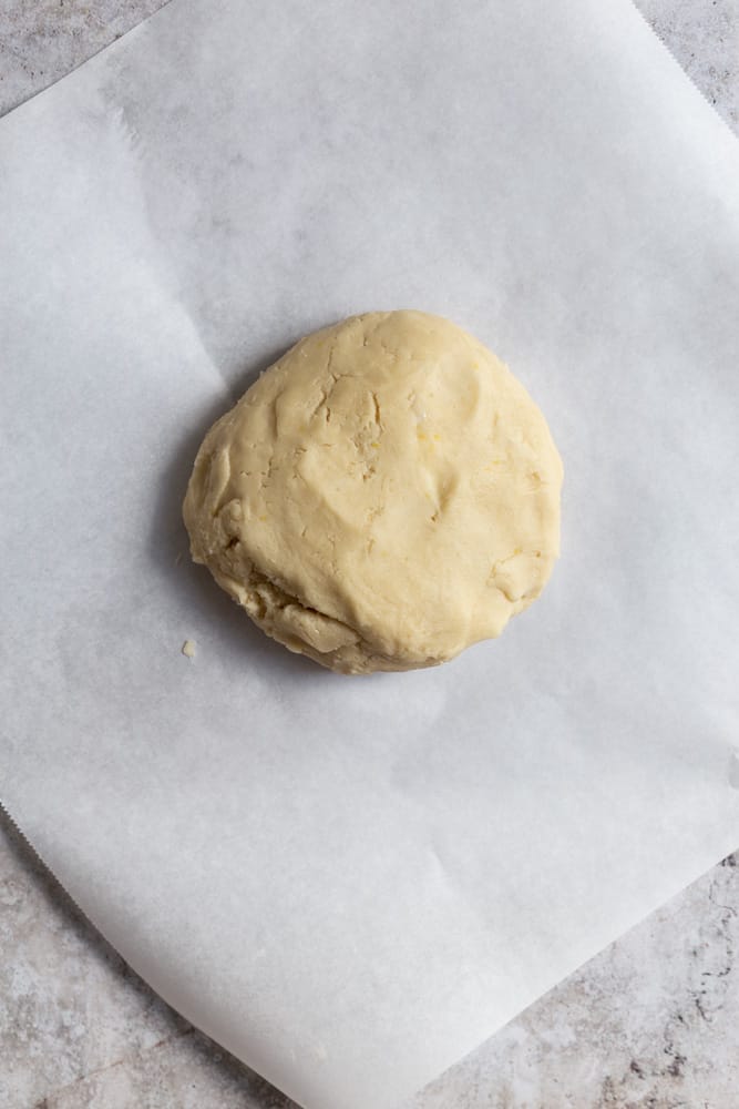 Cookie dough shaped into a disc sitting on parchment paper