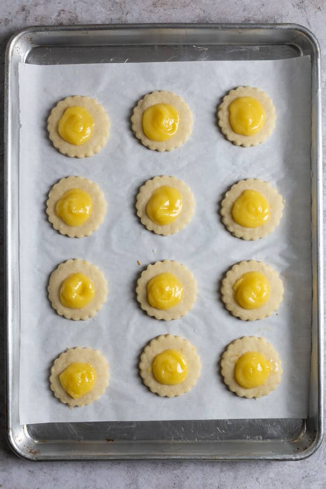 Shortbread cookies topped with lemon curd on parchment paper