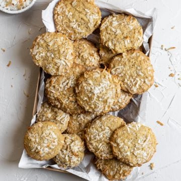 Coconut cookies in a parchment paper lined tray on a white background