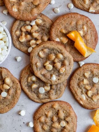 orange cookies with white chocolate chips on a gray surface