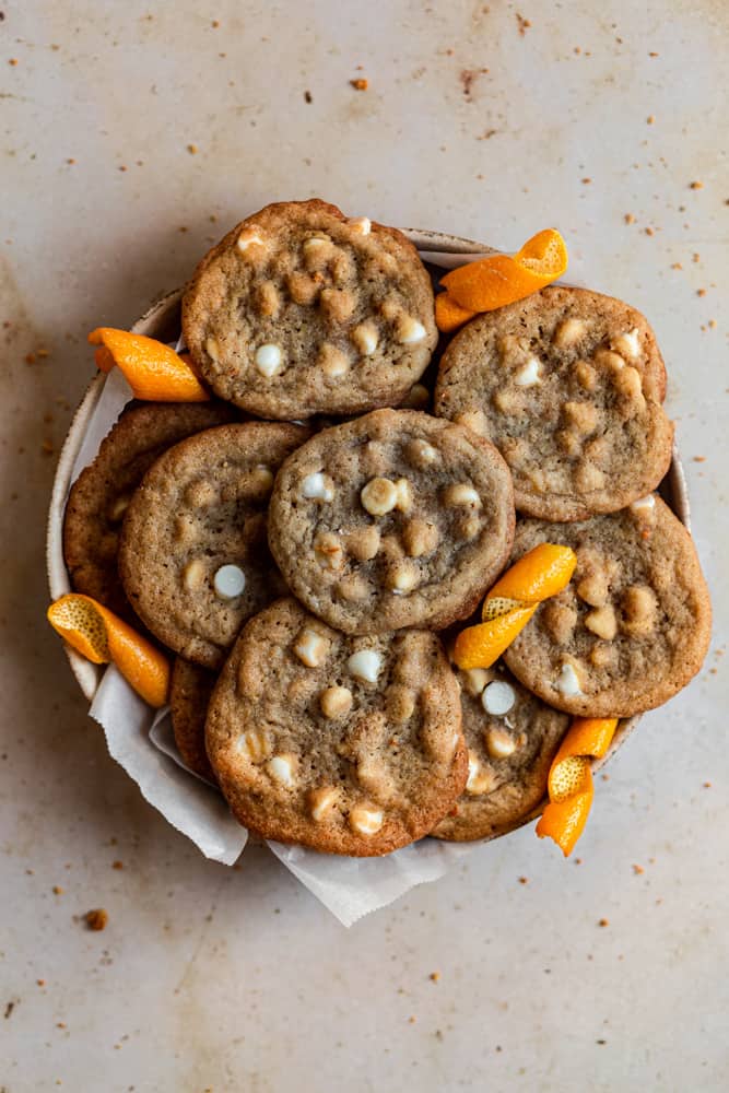 Orange cookies in a bowl on a beige surface.