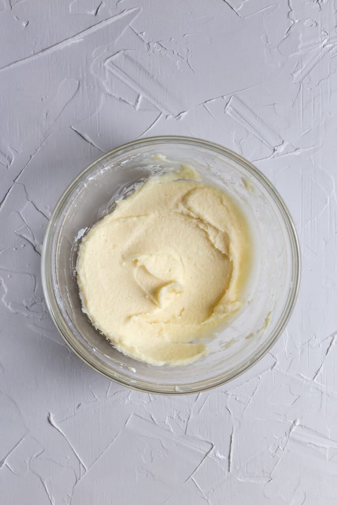 Mascarpone frosting whipped with sugar in a glass bowl.