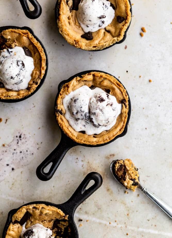 Mini skillet chocolate chip cookies on a beige surface