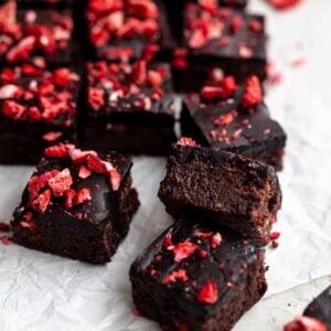 Brownies with strawberries on top on a piece of parchment paper